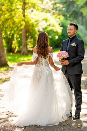 Beautiful wedding gown with flowing train showcased in sunlit forest setting.