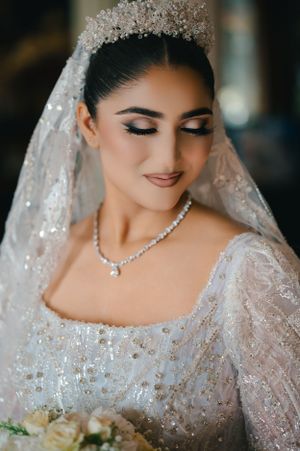 Close-up portrait showing intricate bridal crown, necklace and detailed lace gown.