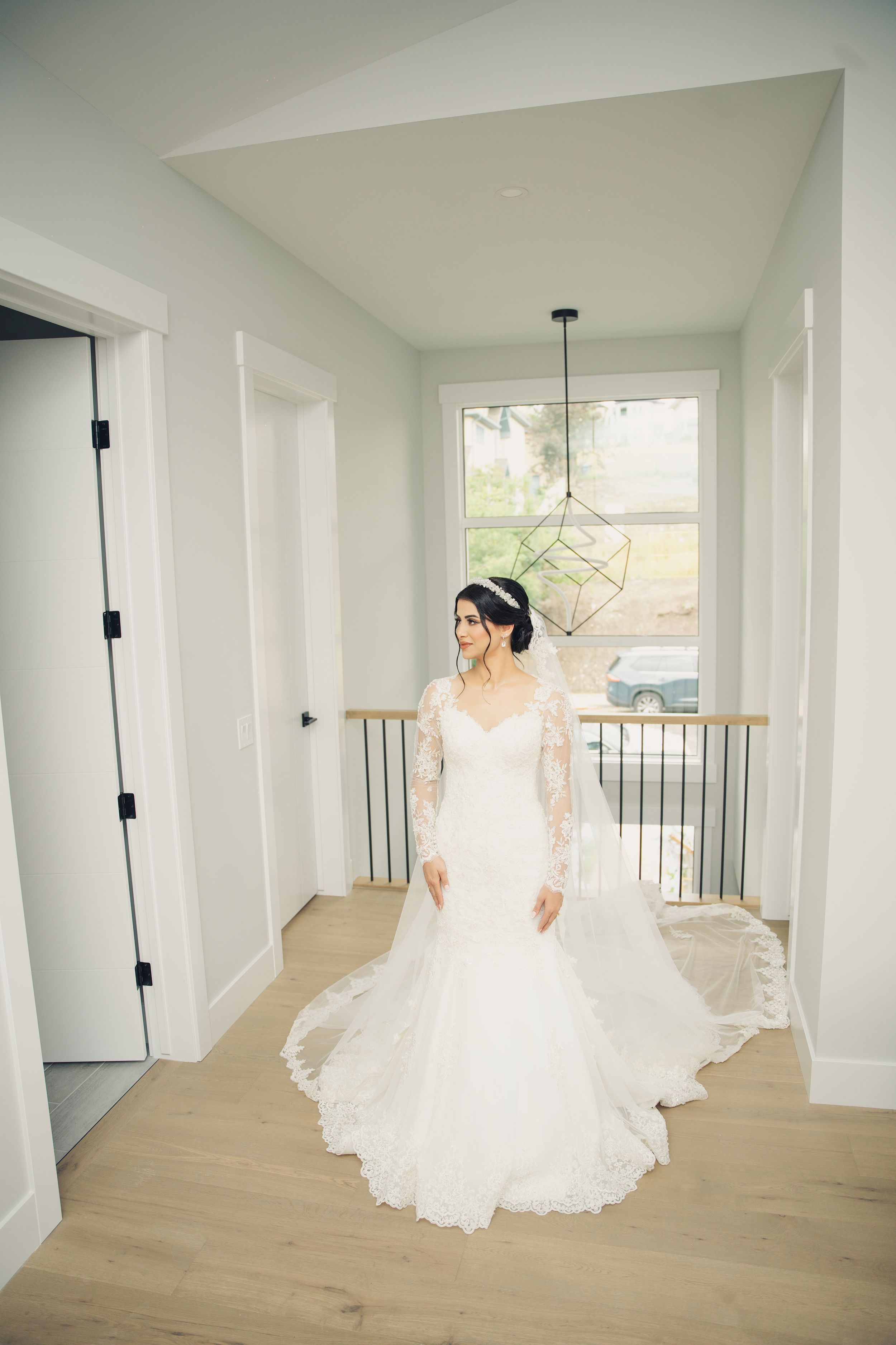 Full-length bridal portrait in modern white hallway with geometric pendant light.