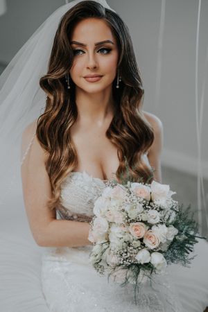Elegant bridal portrait featuring a white floral bouquet and delicate lace wedding gown.