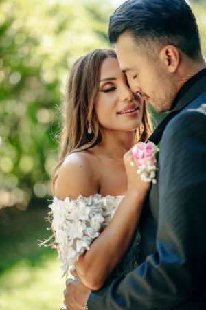 Romantic outdoor wedding portrait with soft natural lighting and pink floral bouquet.