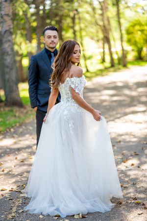 Elegant bridal gown with lace details and flowing skirt captured in forest setting.