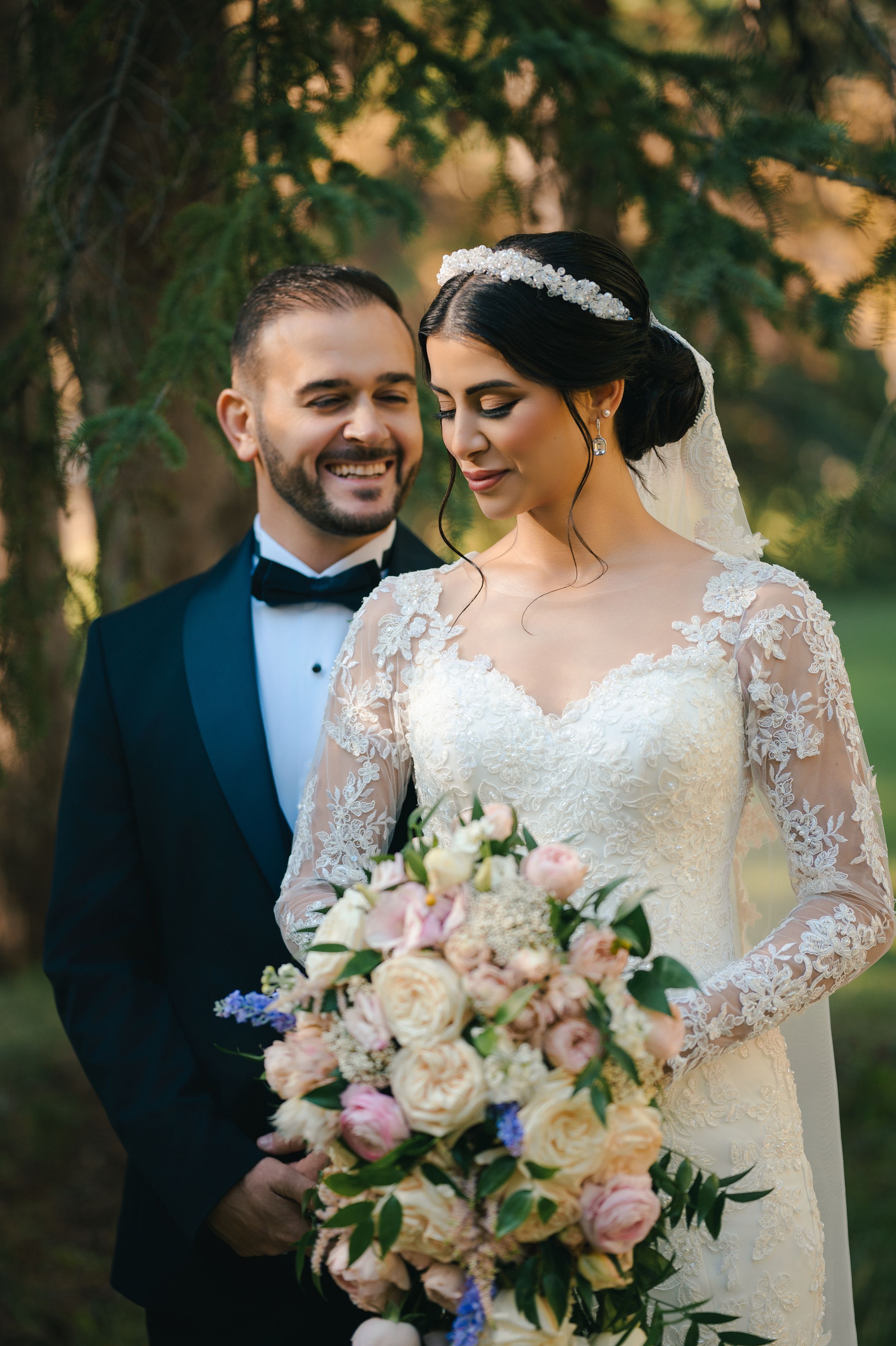 Elegant wedding couple pose with pastel bouquet featuring roses and delicate flowers.