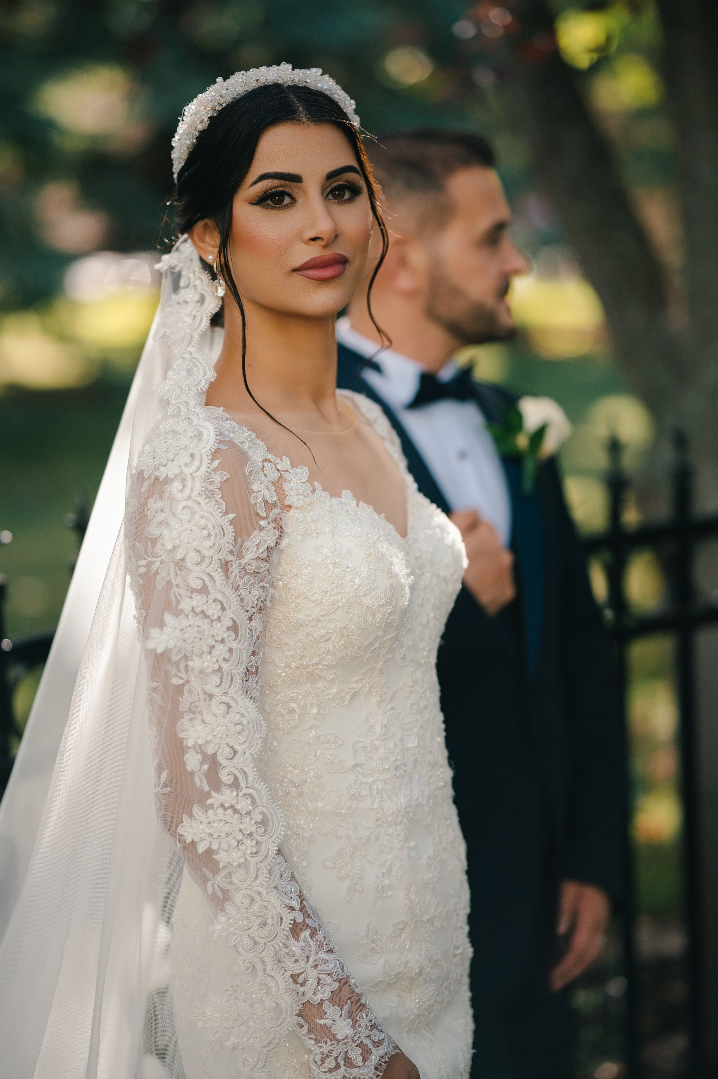 Stunning bridal portrait featuring lace gown and crystal headpiece in garden setting.
