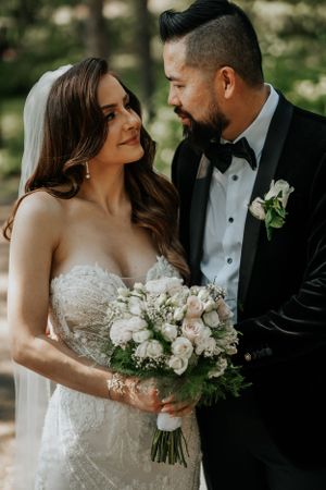 Romantic wedding photo with soft pink and white bouquet against a natural outdoor setting.
