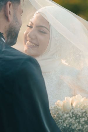 Joyful wedding moment captured between couple with white roses and baby's breath bouquet.