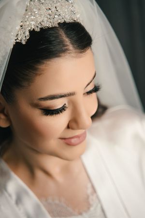 Close-up shot of bridal makeup showing long eyelashes and crystal-adorned veil.