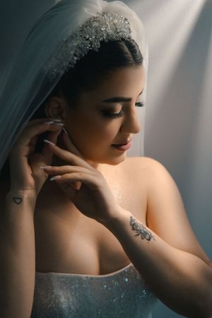 Artistic bridal portrait showing delicate jewelry and strapless gown in soft lighting.