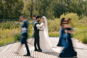 Motion blur of wedding party walking on wooden boardwalk outdoors.