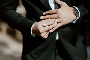 Detail shot of hands showing wedding ring and luxury watch with formal attire.