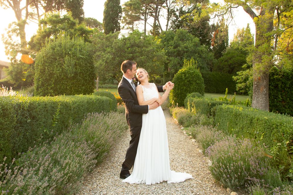 Wedding couple poses on garden path at golden hour surrounded by lavender.