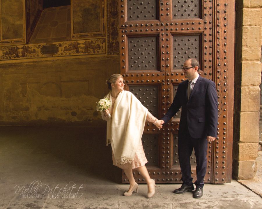 Couple playfully poses by ornate vintage door at historic building.