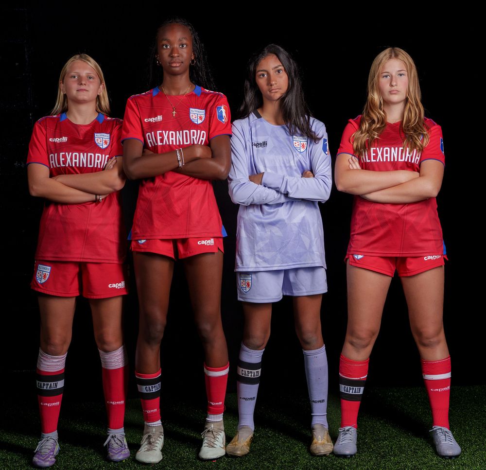 Soccer players in red and white uniforms stand together for a team photo showing their colorful knee-high socks.