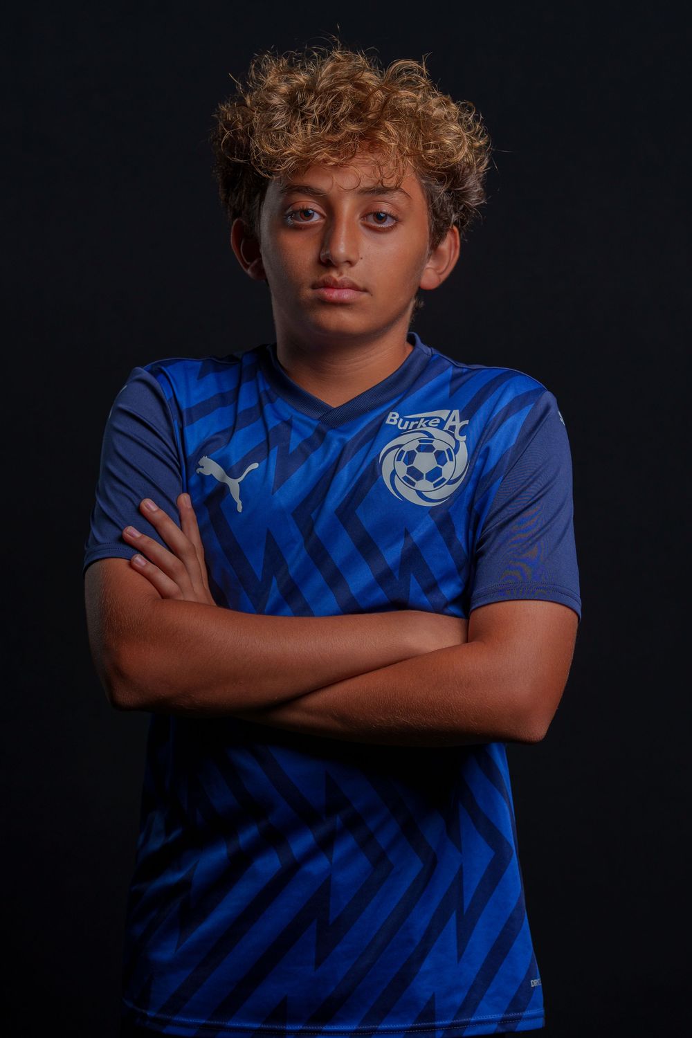 Athletic figure poses in blue patterned soccer jersey against dark background in series of dramatic sports photos.
