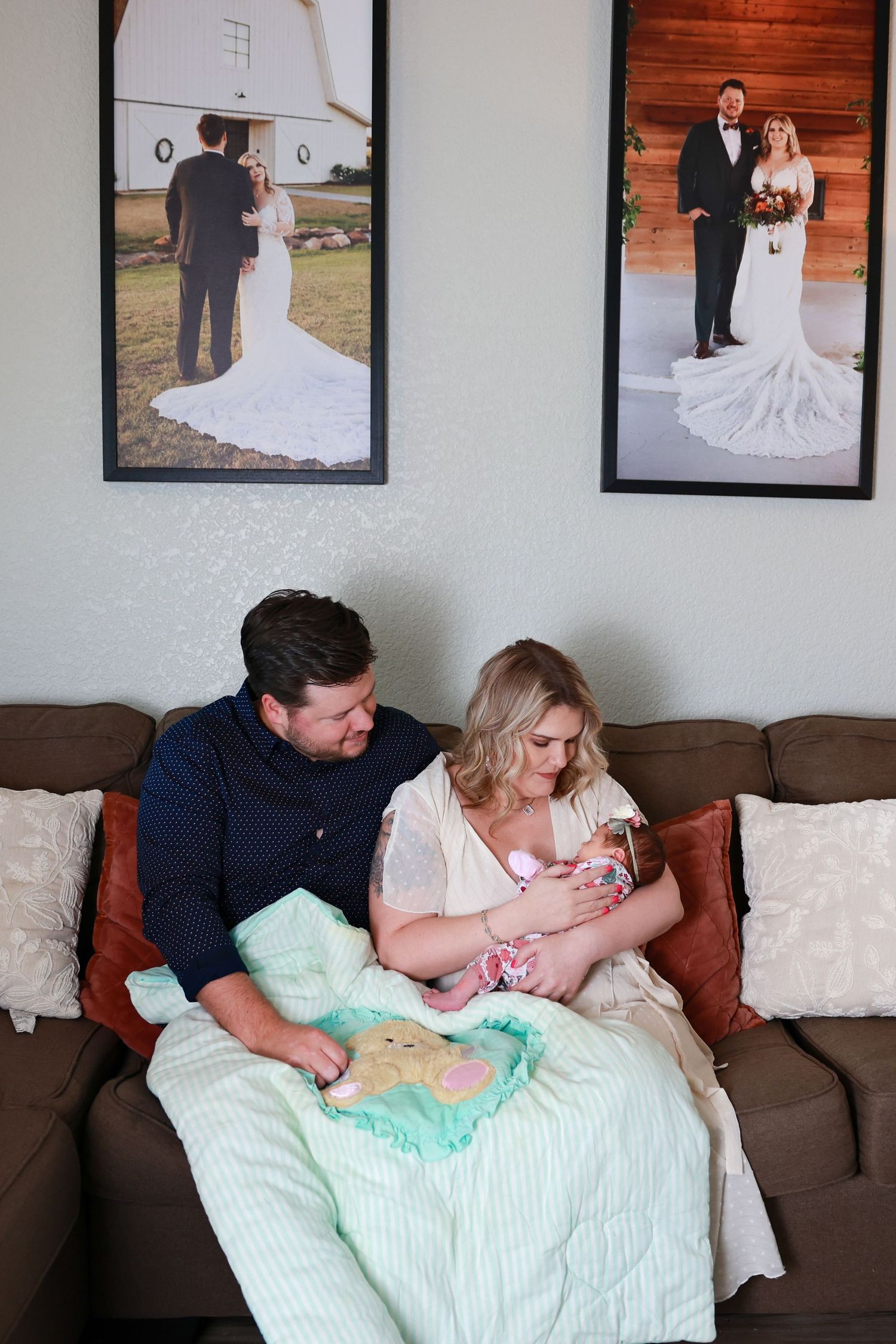 A couple sitting on a brown couch with their newborn baby Carlsbad Roswell Artesia Hobbs New Mexico NM lifestyle in home newborn pictures