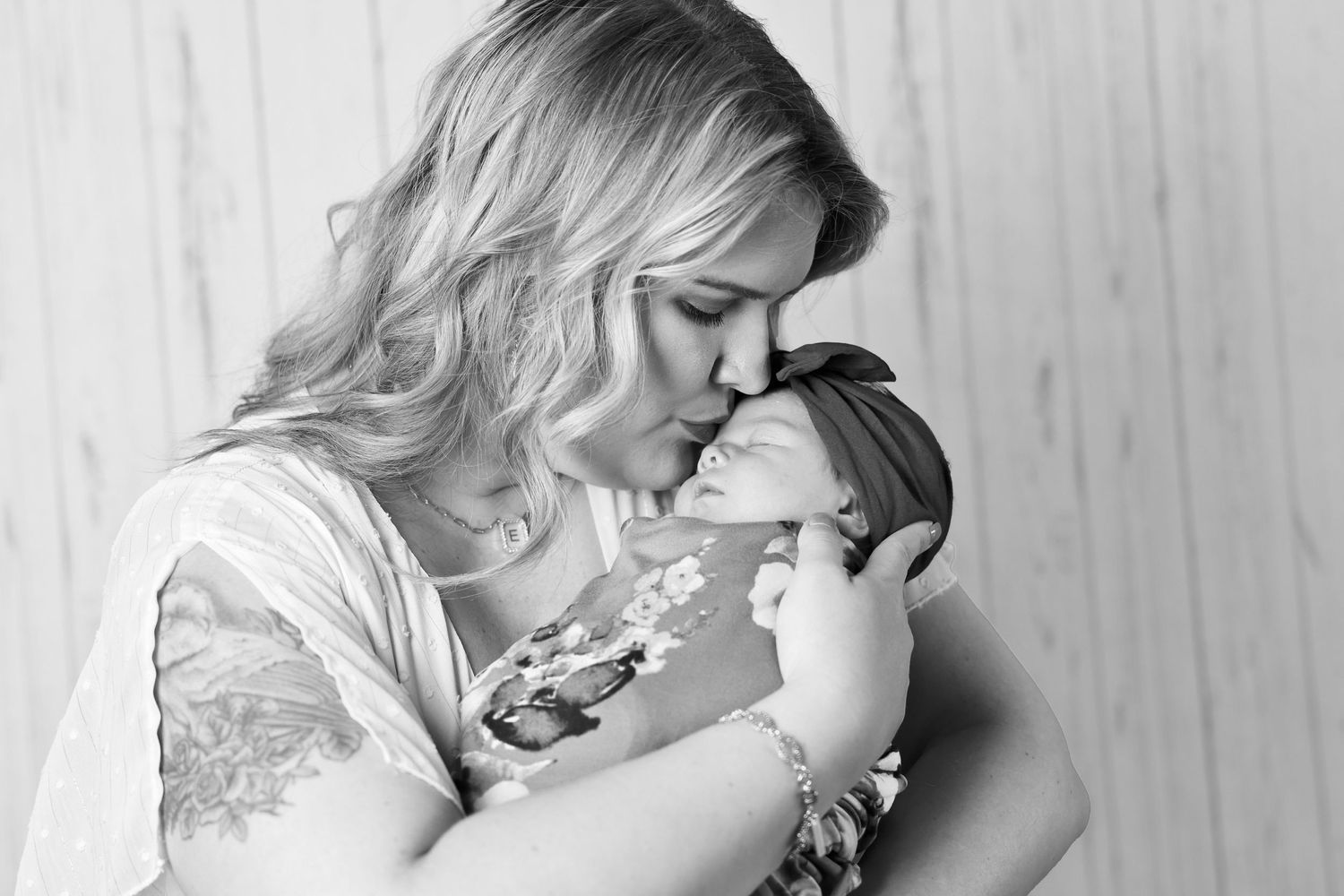 A tender black and white photograph captures an intimate moment between parent and newborn in home new session Carlsbad, Roswell, Hobbs NM
