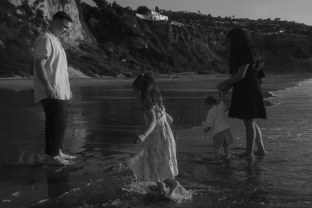 A black and white capture of a family enjoying playtime at the beach.