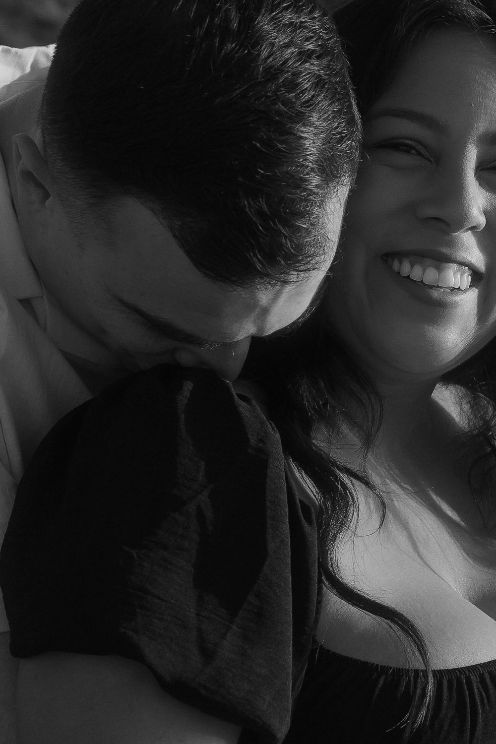 An intimate black and white portrait of a couple sharing a tender moment.