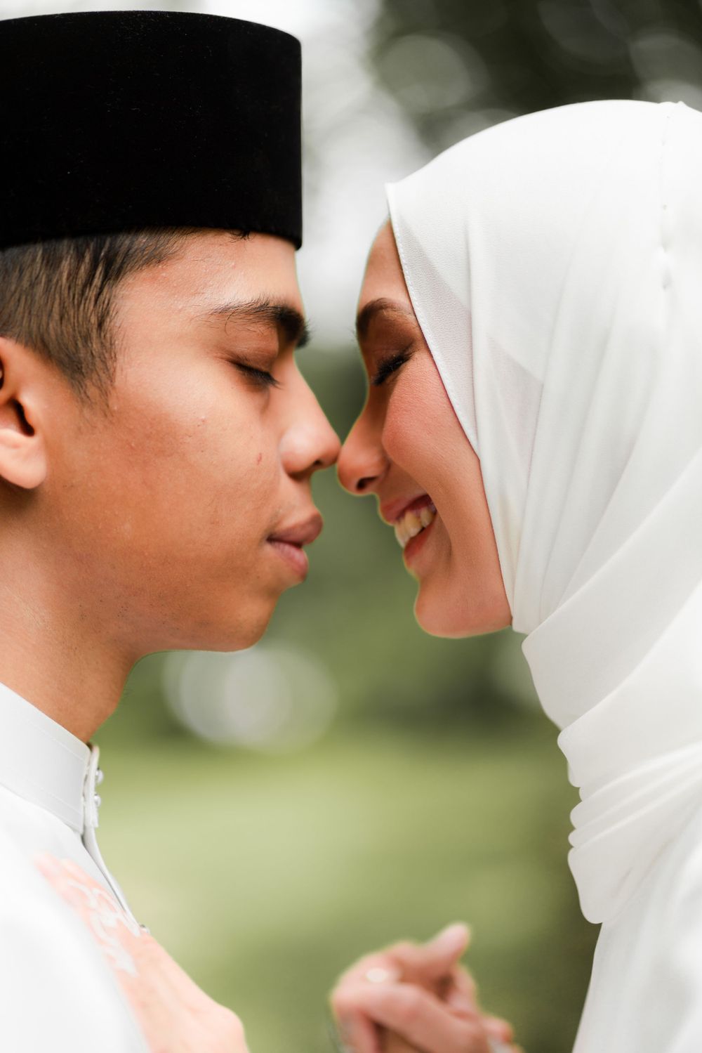 A close-up of a Muslim couple in traditional white wedding attire sharing an intimate moment.