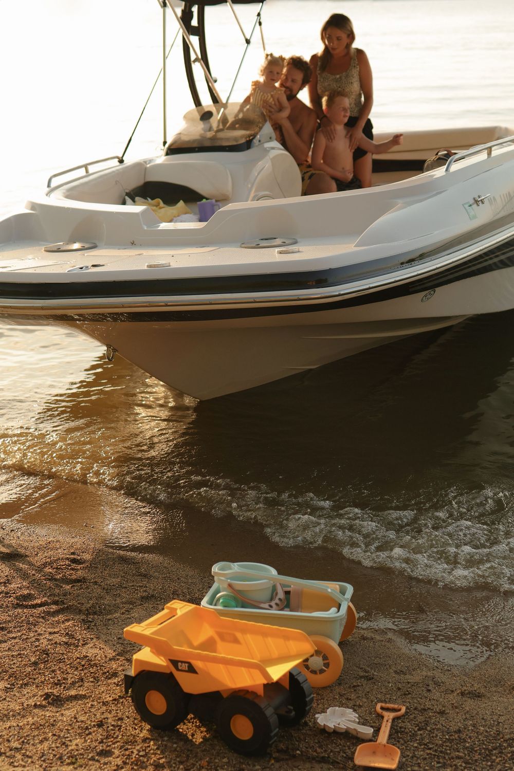 Small boat cruising along calm waters at sunset with orange reflections on the surface.