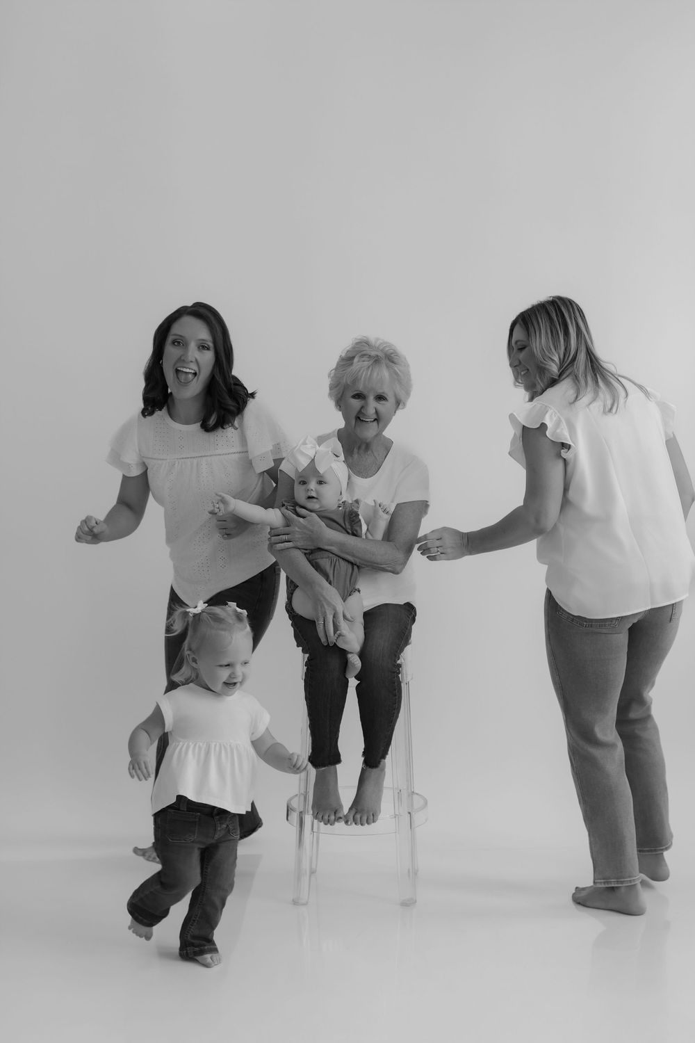 Series of black and white photos showing playful interaction between adults and a toddler learning to walk.