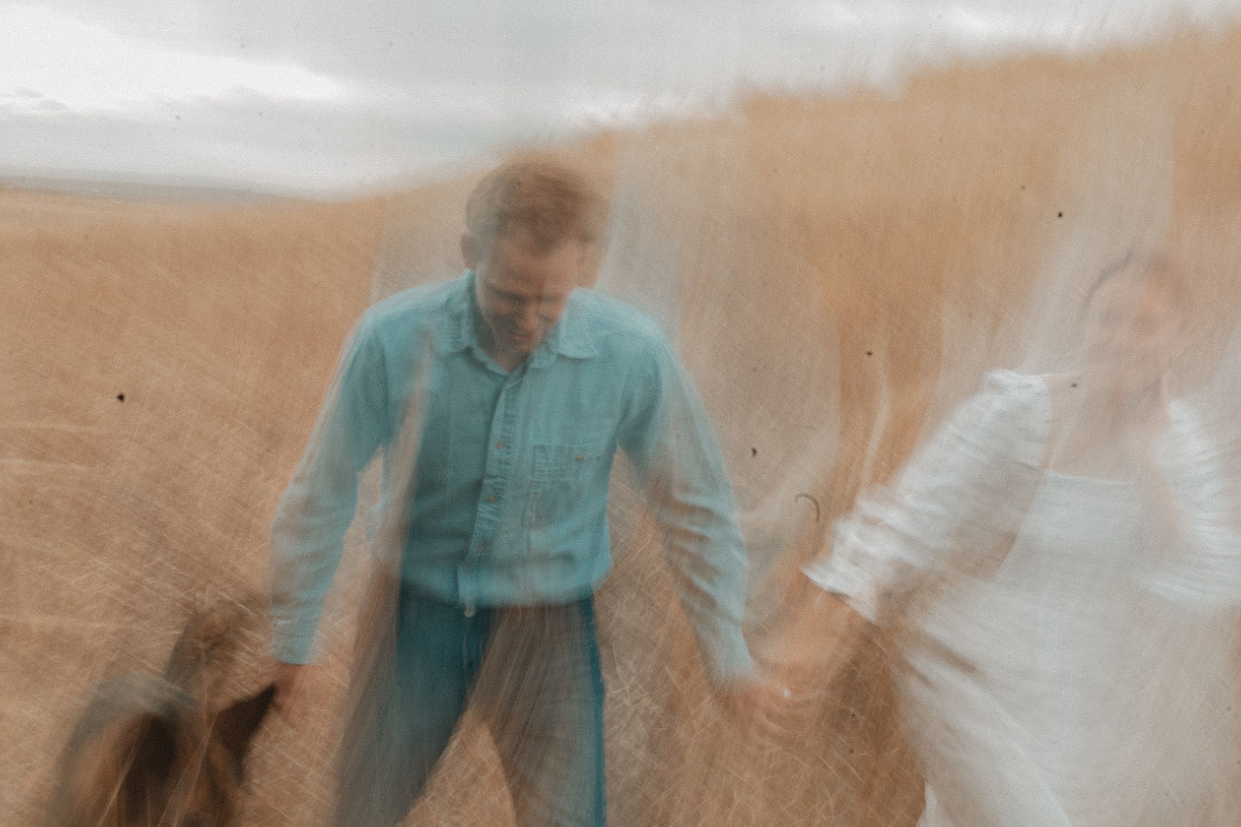 A series of vintage-style photographs in teal and sepia tones showing someone in a flowing dress walking through a field.