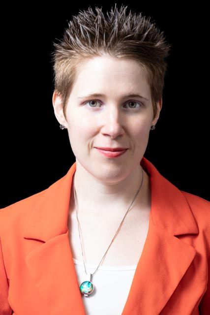 A person in a bright orange blazer and white shirt rests their head on a wooden table in a sequence of similar poses.