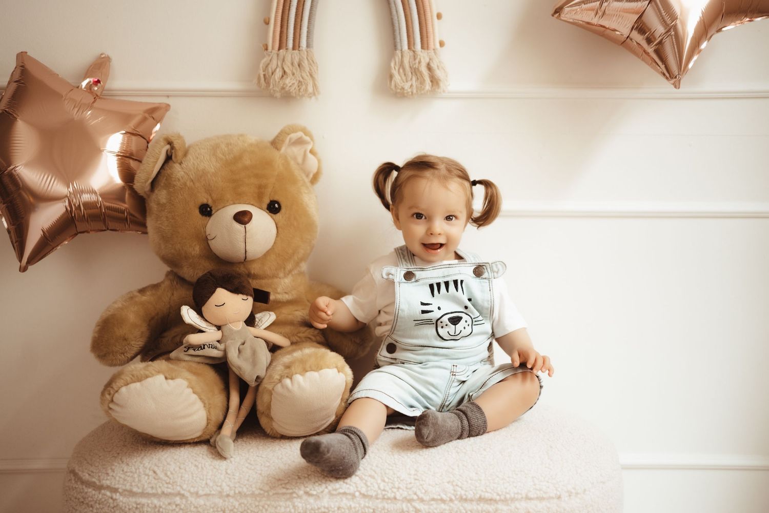 A collection of plush teddy bears and star-shaped balloons arranged on a white wooden background.