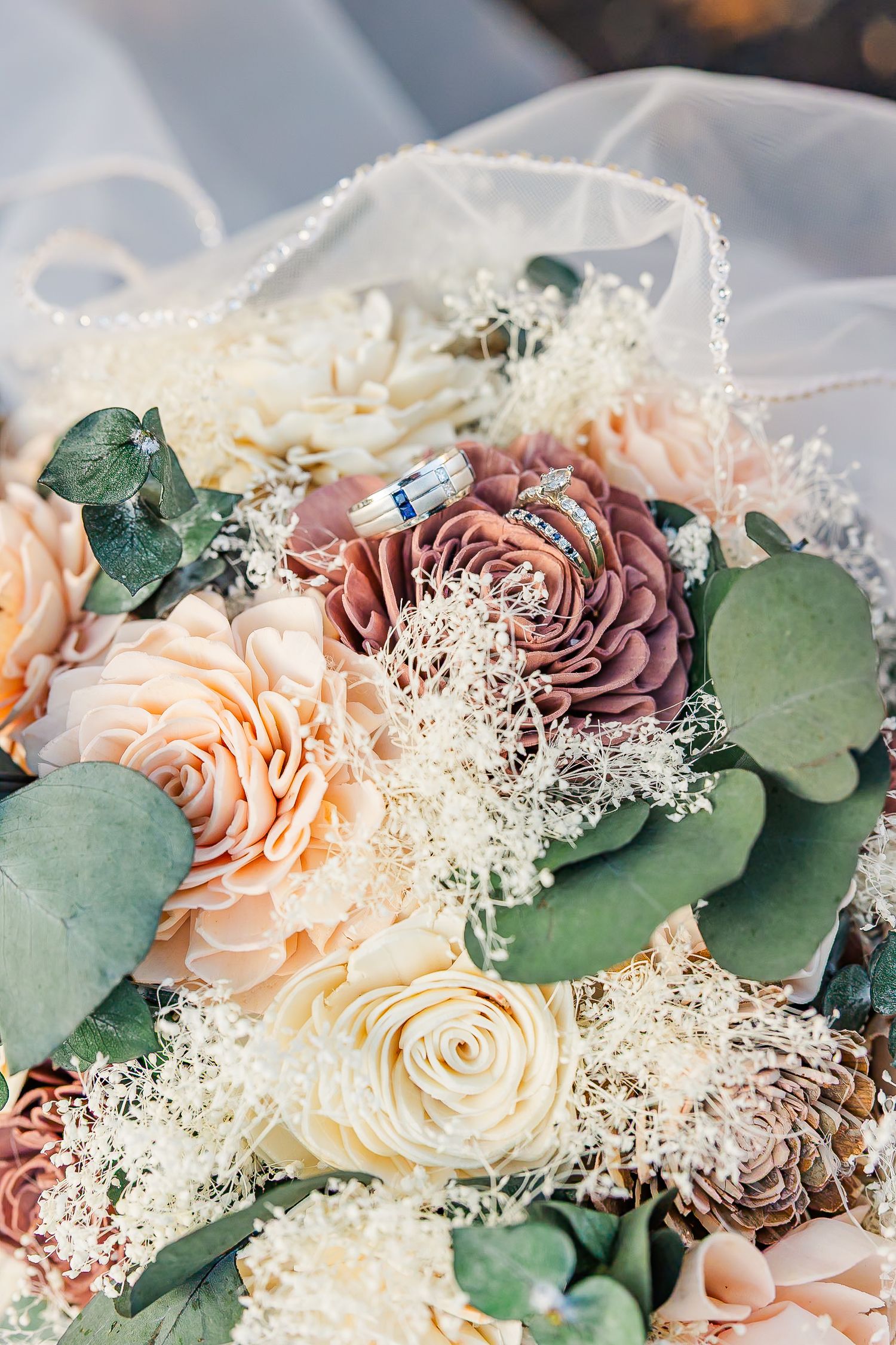 Close-up of romantic wedding bouquet with mauve and peach roses, delicate baby's breath, and eucalyptus leaves.