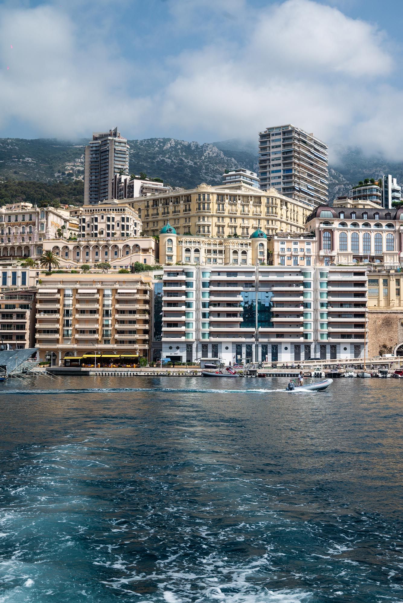 Panoramic view of Monaco's waterfront buildings and luxury apartments along the Mediterranean coastline on a sunny day.