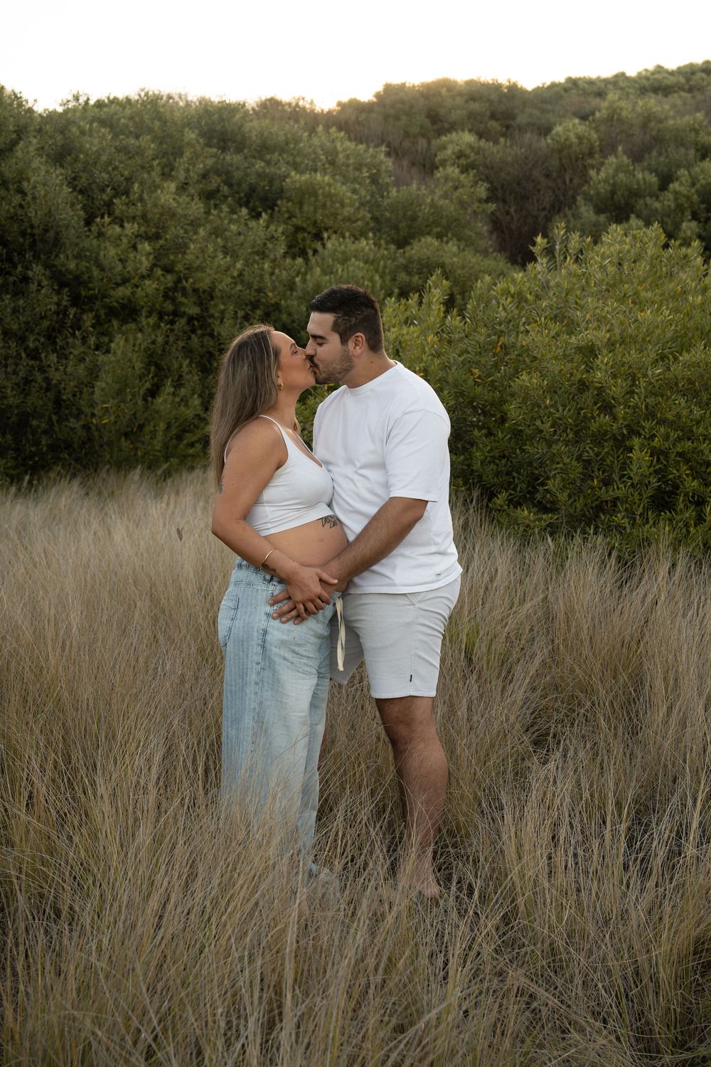 Maternity photography in Wollongong, first-time mum standing in long grass, glowing with joy.
