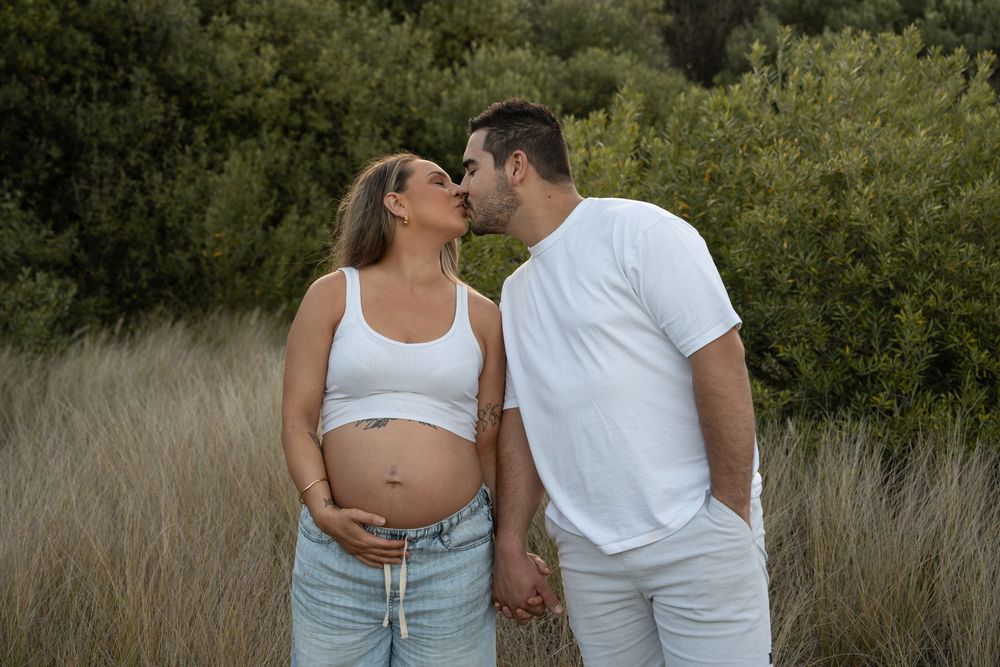 Soft golden light over long grass during maternity photoshoot in Wollongong with expecting mum and dad