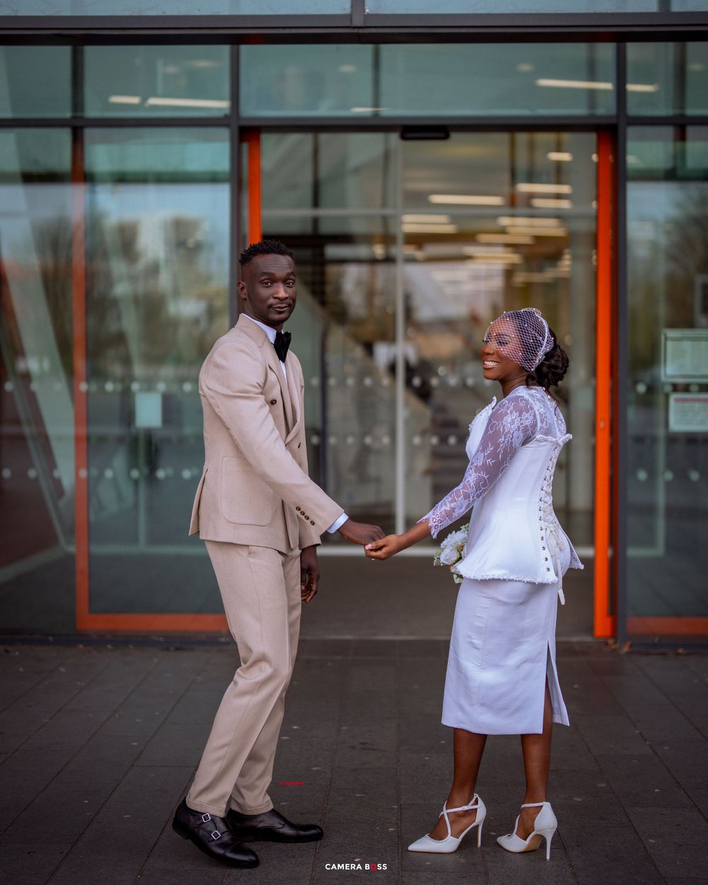A couple shares a romantic moment while dancing together outside a modern glass building.