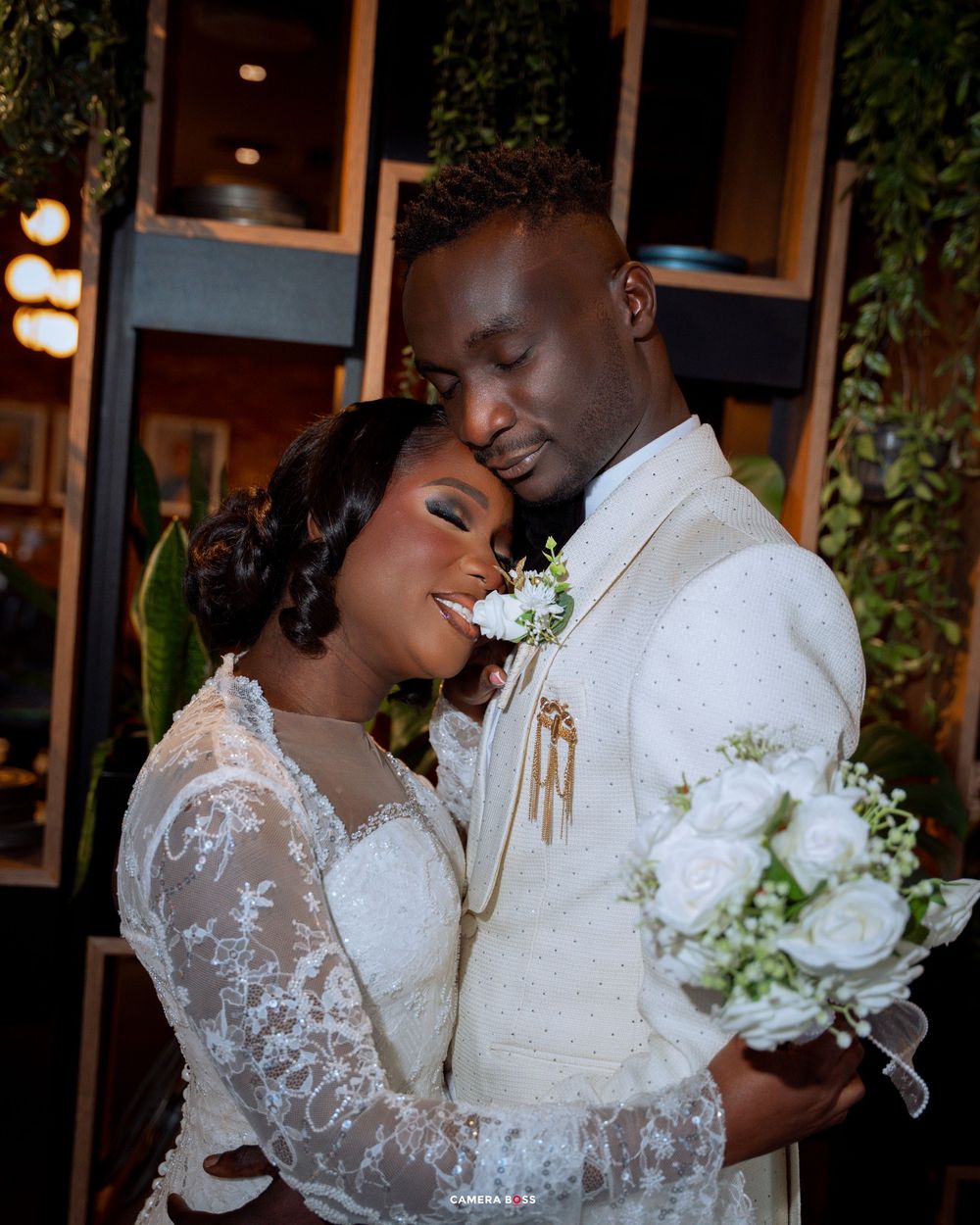 Romantic wedding couple shares intimate moments in an elegant indoor setting with soft lighting and floral decor.