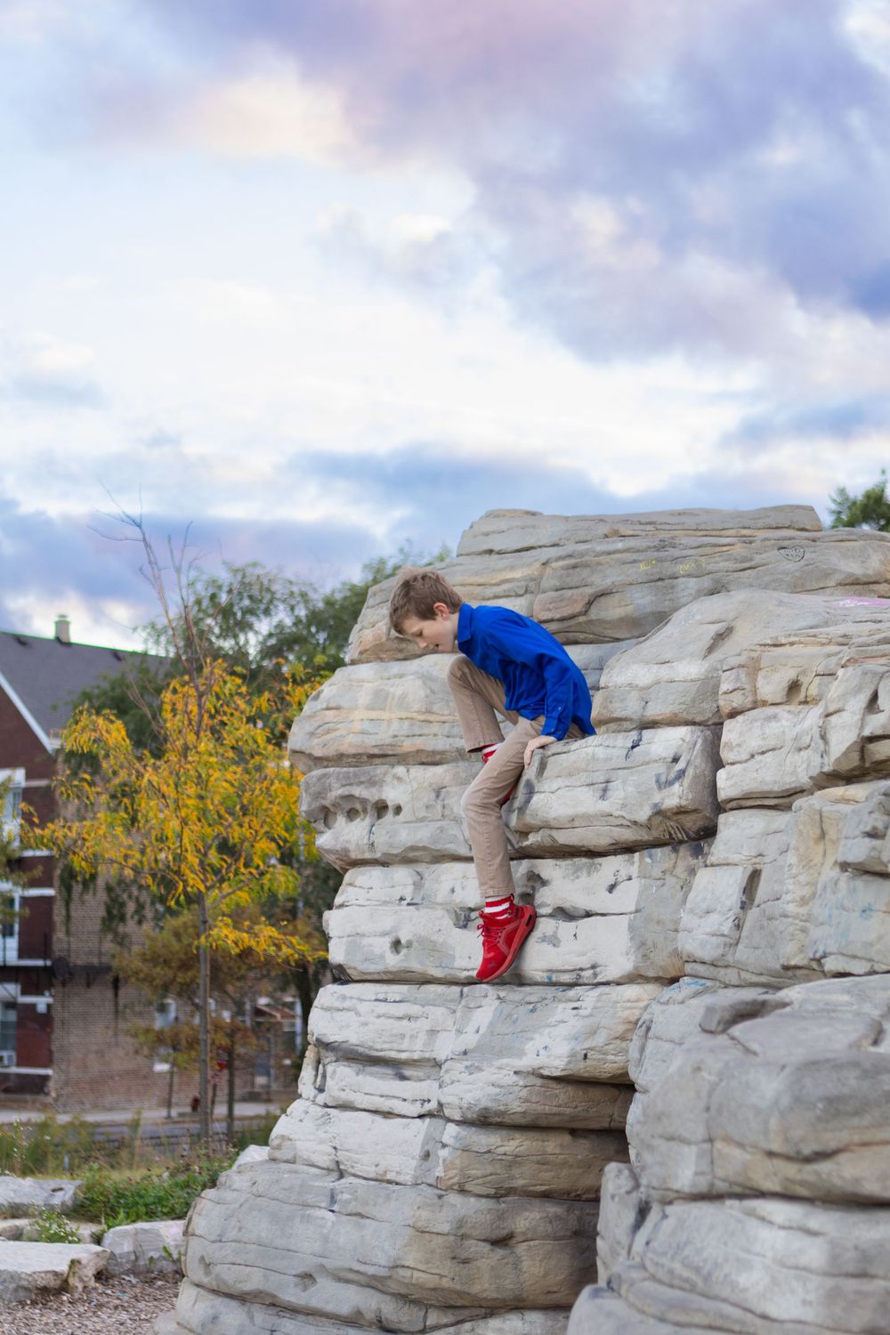 Kids climbing and exploring large limestone rocks in an outdoor park.