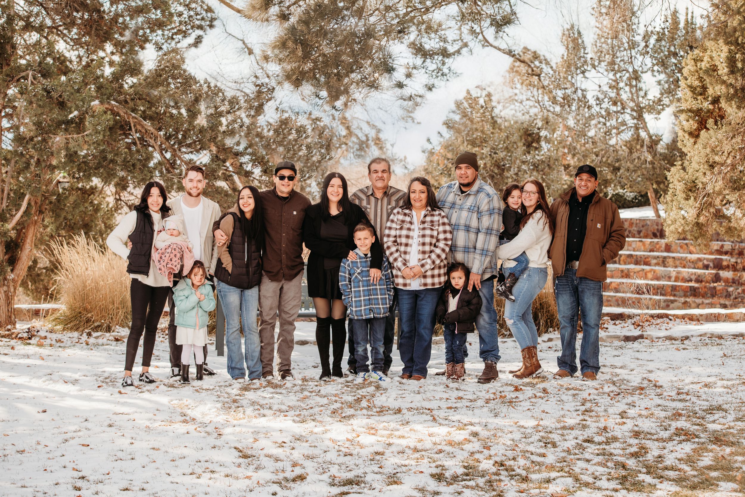 Family group hugging and laughing together against autumn foliage background.