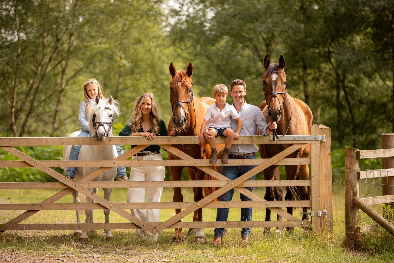 Two joyful riders lean over a white horse's back in a sun-drenched field at golden hour.