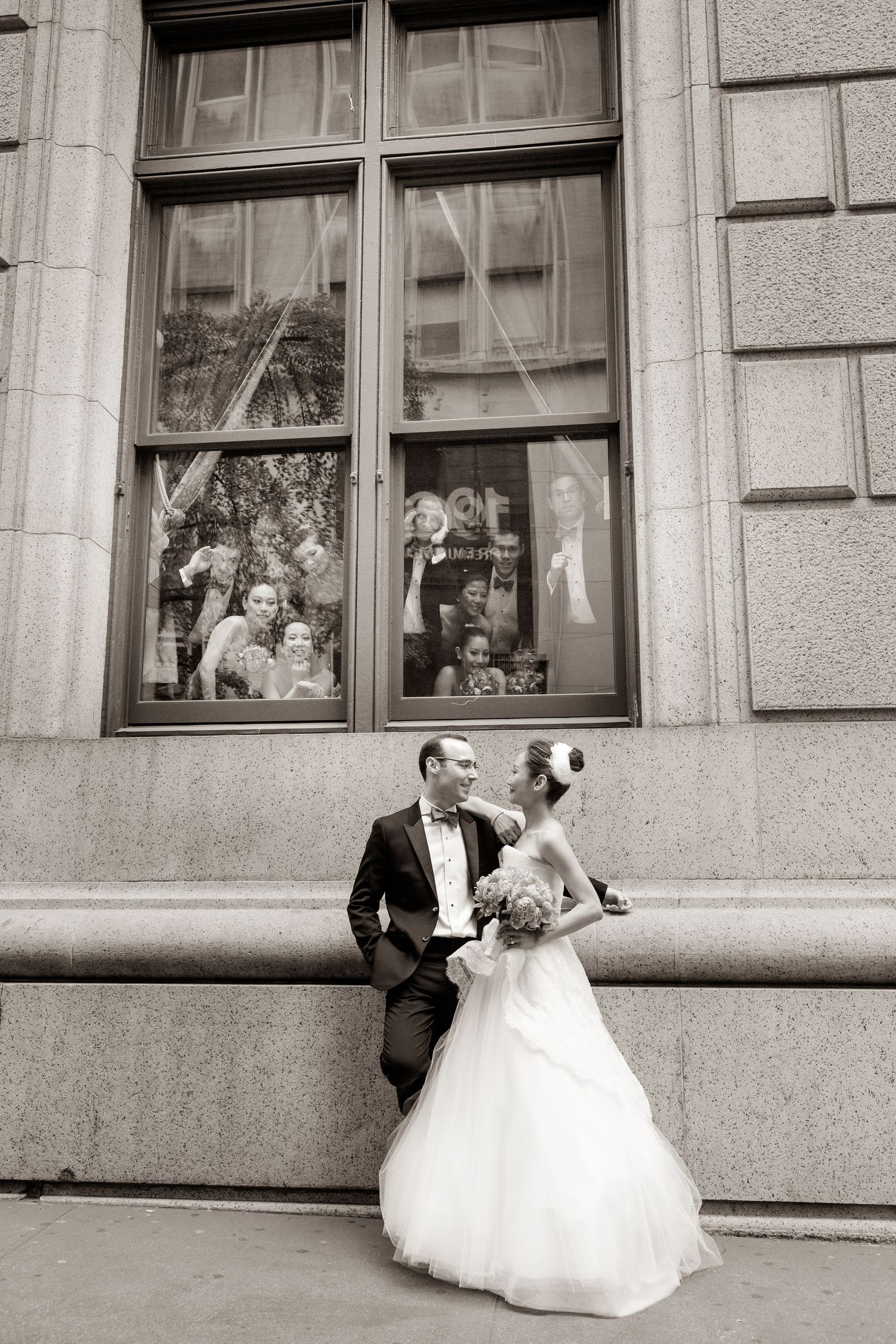 A sequence of wedding photos showing a couple posing playfully in front of a historic building's windows.