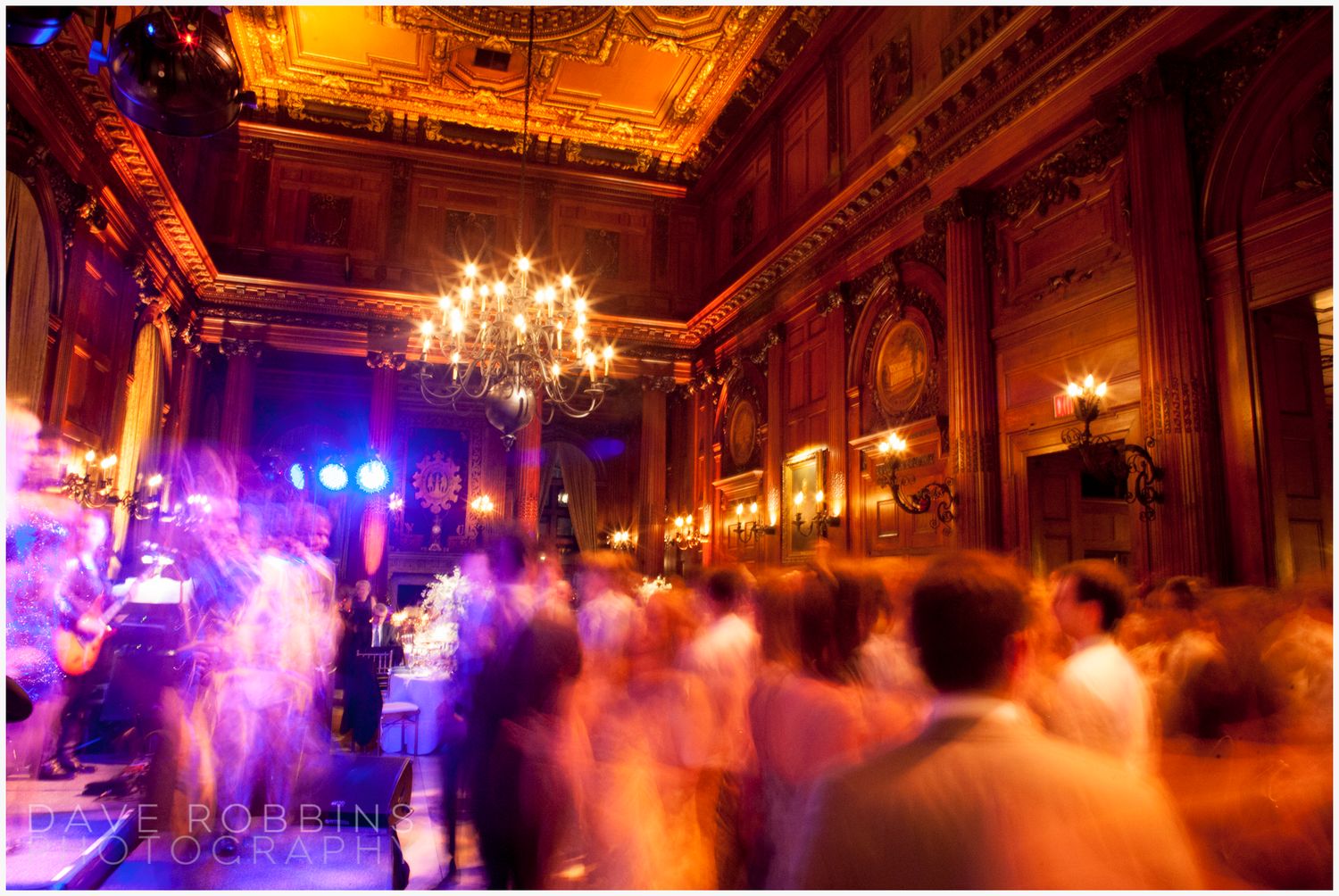 Elegant ballroom illuminated by warm chandeliers and colorful stage lights creates a dramatic atmosphere for an evening event.