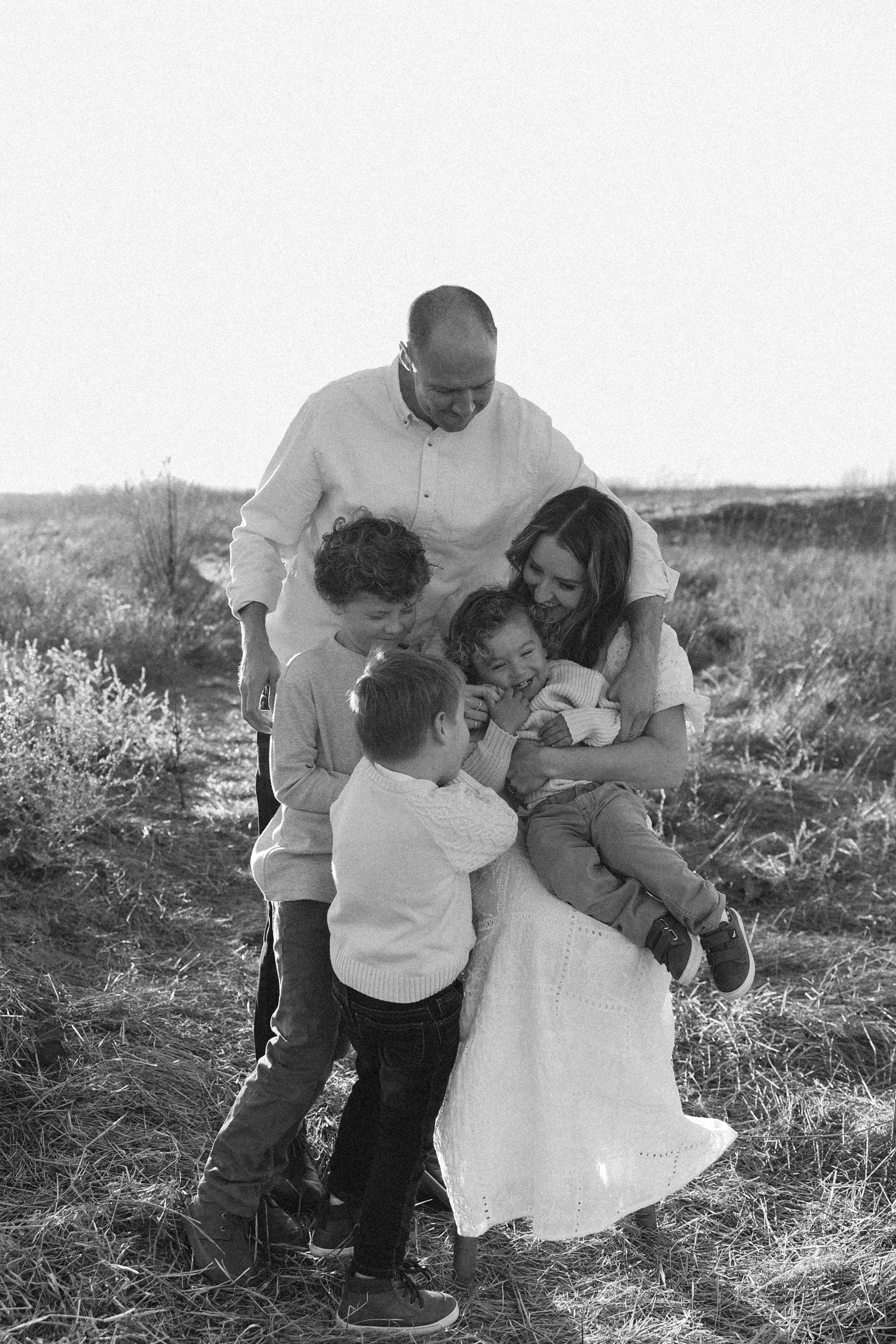 Family of five laughing together during sunset field session in Orange County family photography