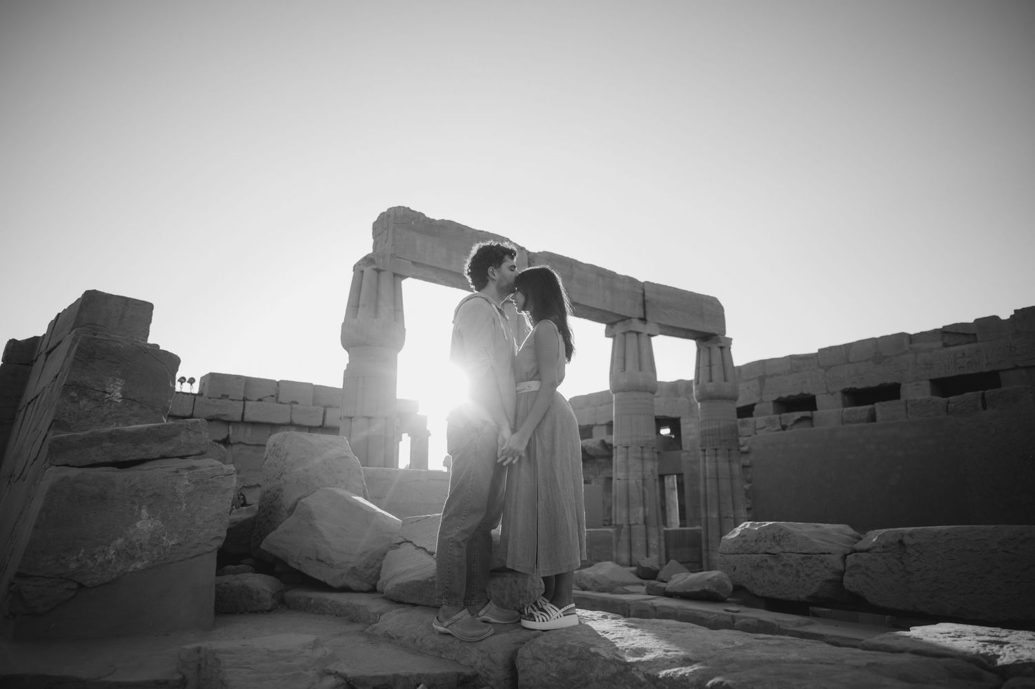 A group poses together in front of ancient Egyptian statues and ruins at Abu Simbel temple.