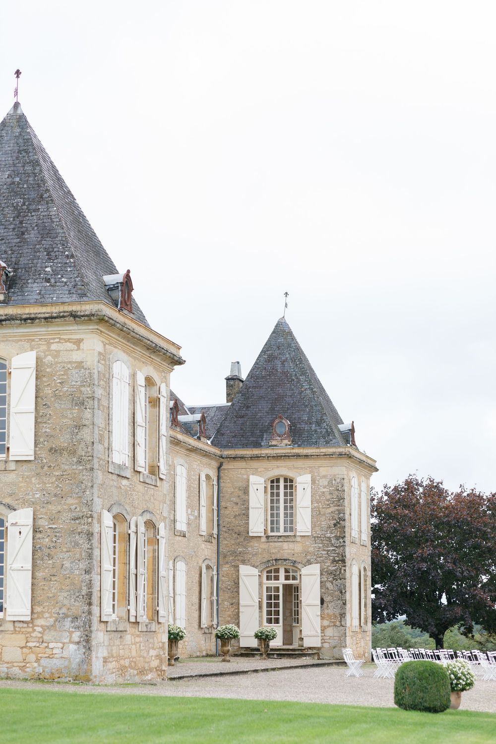Exterior view of a grand French chateau with stone walls, turrets and classic architecture in the countryside.