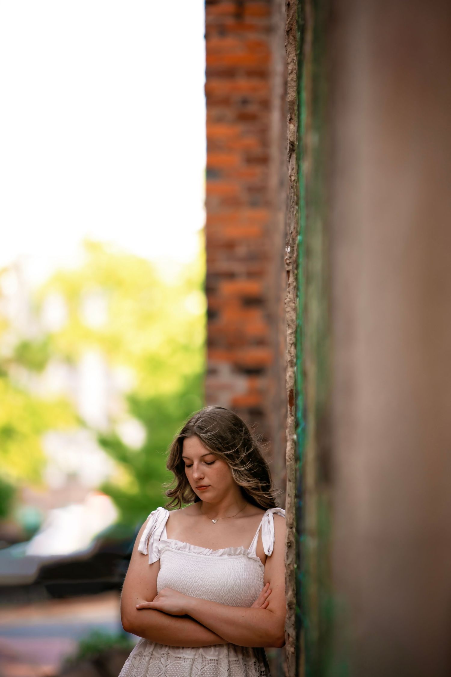 Portrait session by brick wall with soft natural lighting and vintage architectural elements.