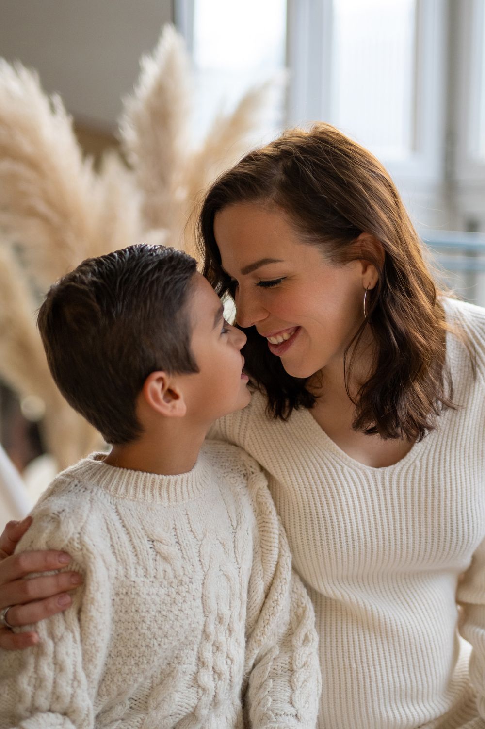 A heartwarming moment between family members wearing cream-colored knit sweaters as they share tender embraces.