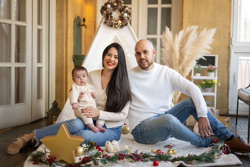 Family sitting on floor at home playing with colorful blocks and toys together in living room.
