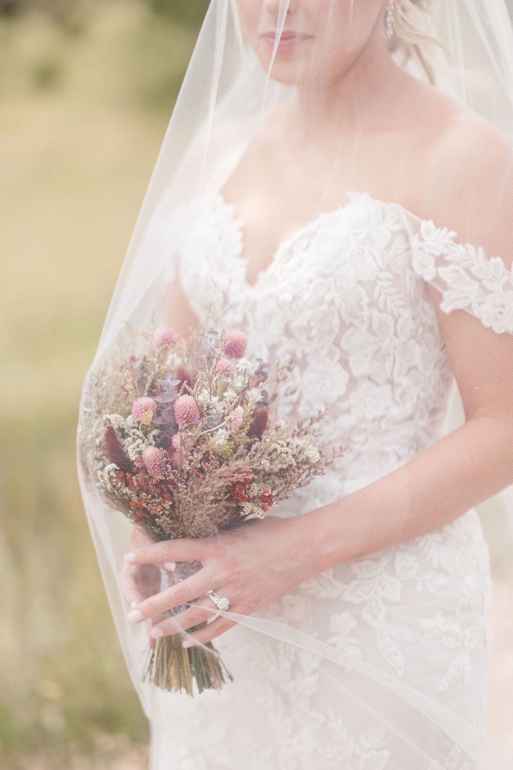 Close-up of a bridal bouquet with dried flowers and delicate lace details on a wedding dress.