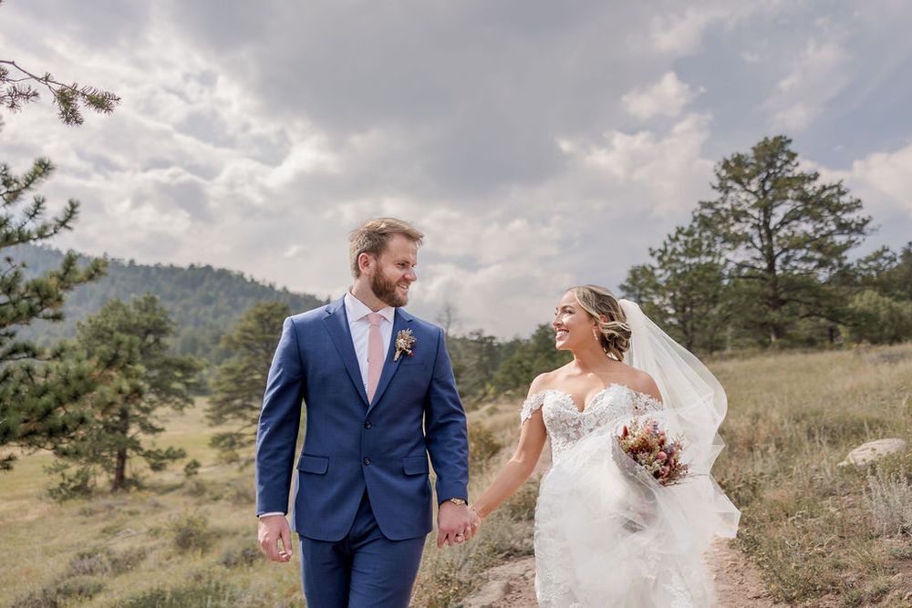 A couple shares an intimate moment on a grassy mountain overlook during their wedding day.
