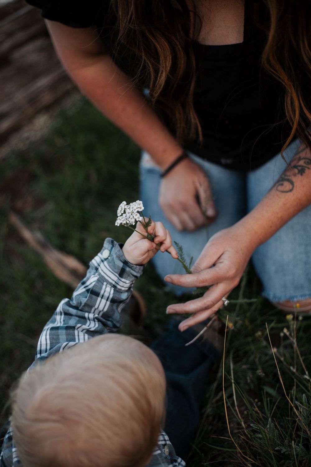 Close-up view of hands holding a plaid flannel shirt while sitting in grass outdoors.