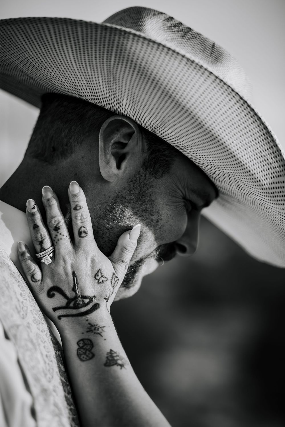 Black and white close-up photos showing hands with small tattoos and a cowboy hat in a series of artistic shots.