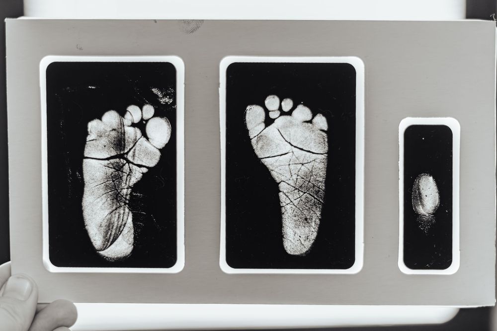 A series of black and white photographs showing baby footprints arranged in a horizontal row.